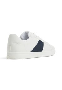 Vita lädersneakers med en strukturerad marinblå accent på sidan, platt gummisula och snördesign. Slät innervaddering.