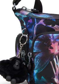 Blomstermønstret crossbody taske i sort stof, med en lynlås lomme, metalhardware og en sort gorilla nøglering som accent.