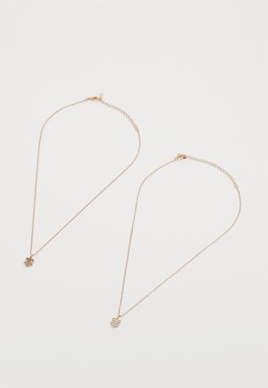 Auksinės spalvos kaklo grandinės su subtiliais granuliais, dekoruotos dėlionės formos pakabukais. Vienas pakabukas turi mažų skaidrių akmenukų, kad pridėtų detalių.