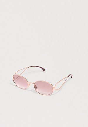 Round rose-tinted sunglasses with thin gold metal frames and intricate gold chain temple arms on white background.