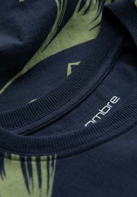 Marineblauwe t-shirt met een groen abstract patroon, van katoen, met een geribbelde ronde halslijn en een klein label met de tekst "ombre."