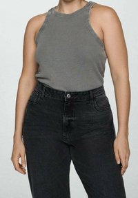 Szary prążkowany top na ramiączkach zestawiony z wysokimi czarnymi dżinsami, które mają zapięcie na guziki i przednie kieszenie. Klasyczny, swobodny styl.