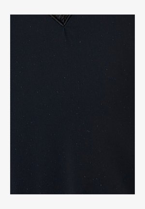 Tissu noir avec une texture côtelée parsemée de petites speckles, agrémenté d'un accent en forme de diamant au niveau de l'encolure.