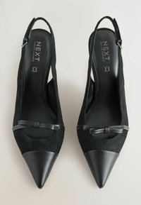 Décolleté nere slingback in suede con punta nera liscia e appuntita, caratterizzate da un dettaglio a fiocco e un elegante cinturino alla caviglia.