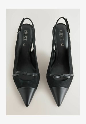 Czarne zamszowe szpilki na odkrytej pięcie z wąskim noskiem, z akcentem w postaci czarnej skórzanej wstążki oraz gładką, błyszczącą osłoną noska. Szczegóły w kolorze srebrnym.