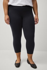 Marineblauwe capri leggings van rekbaar materiaal, met een gladde textuur en een hoge tailleband, gecombineerd met zwarte ballerina's.