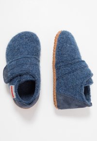 Chaussons en feutre bleu avec une semelle en caoutchouc, une sangle élastique et une texture douce. Caractéristiques : bout arrondi et design minimaliste.