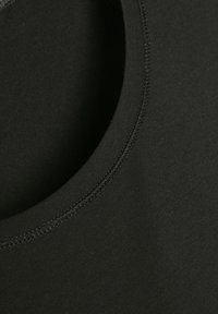 Close-up van een zwarte stof met een zichtbare dubbelgestikte naad langs een gebogen rand, waarbij de textuur en de details van het stiksel worden benadrukt.