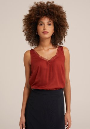 Rotes ärmelloses Oberteil mit Spitzenbesatz am Ausschnitt, aus glattem Stoff; kombiniert mit einem dunklen Rock. Einfaches und klares Design.