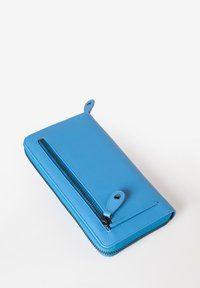 Portafoglio blu in pelle con una texture liscia, chiusura con zip e due anelli decorativi sulla parte superiore. Presenta dettagli della cerniera nera.