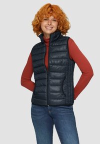 Granatowa kamizelka puchowa z zamkiem z przodu, z poziomym pikowaniem, dwoma bocznymi kieszeniami i wysokim kołnierzem, noszona na czerwonej koszuli z długim rękawem.