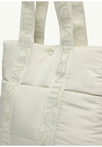White quilted tote bag with textured surface. Features two fabric straps with embossed branding. Button detail on the front.