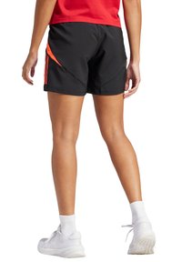 Schwarze Sportshorts mit orangefarbenen Akzenten und drei schwarzen Streifen an der Seite. Leichter Stoff, knielang, mit lässiger Passform.