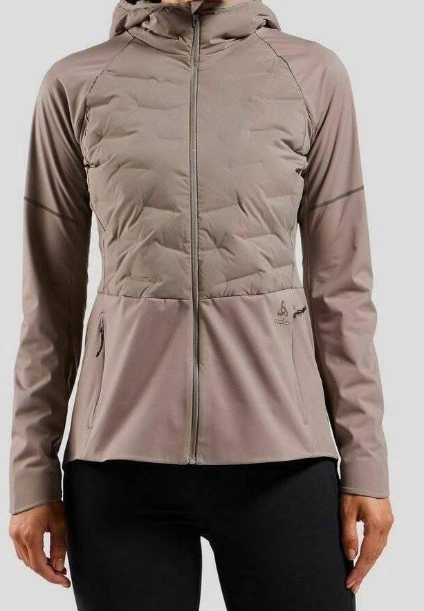 Veste légère taupe avec poitrine matelassée, fermeture éclair devant, capuche, deux poches zippées, portée sur un pantalon noir.