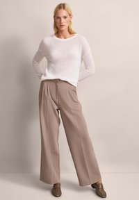Leichtes, durchscheinendes, weißes Langarm-Pullover kombiniert mit lockeren, taubenfarbenen, weitem Hosen und braunen Slippern. Schlichtes, elegantes Design.