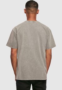 Grijze katoenen t-shirt met korte mouwen, ronde halslijn en een vervaagde textuur. Met contrasterende stiksels langs de zomen.