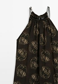 Robe noire sans manches avec fines bretelles, présentant des motifs abstraits circulaires beige irréguliers et un col froncé.