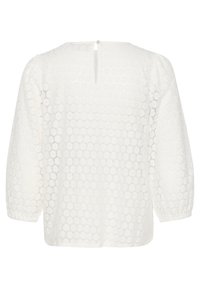 Blouse en dentelle blanche avec manches ballon trois quarts, fermeture dos avec bouton en forme de goutte, et motif circulaire sur tout le tissu.
