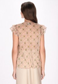 Gennemsigtig floral bluse med rynkede korte ærmer, prydet med et mønster af pink roser og grønne blade på en lys baggrund.