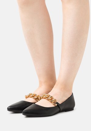 Bailarinas de piel negra con punta afilada, adornadas con una cadena dorada en la parte superior. Diseño de perfil bajo con un tacón redondeado.