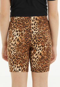 Šortky s leopardím potiskem v hnědé a černé barvě, s hladkou texturou, mají přiléhavý střih a lem, který končí nad kolenem.