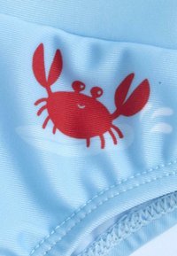 Tela azul clara con un diseño de cangrejo rojo que tiene las garras levantadas, una expresión sonriente y detalles cosidos a lo largo de los bordes.