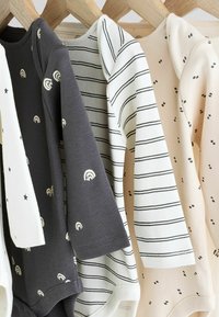 Trois bodies à manches longues en coton : gris foncé avec des imprimés arc-en-ciel, blanc avec des rayures noires, et beige avec des pois noirs, tous avec des encolures arrondies.