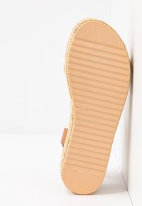 Ljusbrun platåsandaler med en strukturerad gummisula, vävd jute-detalj och en läderspänne i mitten.