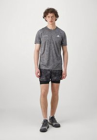 T-shirt atlético cinza com textura mesclada, combinado com calções pretos estampados. Completa o conjunto com sapatos desportivos cinzentos e um design minimalista.