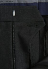 Schwarzer Stoff mit glatter Textur; verfügt über eine Reißverschlusstasche und ein Knopfdetail an der Taille; minimale Nähte sichtbar.