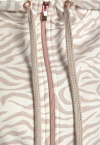 Hooded sweatshirt with a beige and white zebra stripe pattern, featuring a front zipper with rose gold hardware and matching drawstrings.