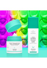 Zwei Hautpflegeprodukte: ein Cremetiegel mit türkisen Deckel und weißem Boden sowie eine Serumflasche mit türkisem Verschluss, vor einem farbenfrohen, glänzenden Hintergrund.