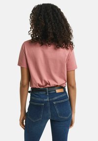 Roze korte mouwen T-shirt met een relaxte pasvorm, gecombineerd met donkerblauwe jeans van denim met twee achterzakken en een leren label.
