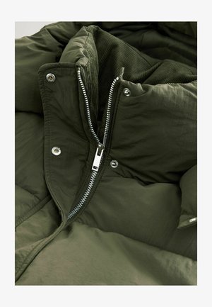 Grüne gepolsterte Jacke aus strukturiertem Stoff, mit einem silbernen Reißverschluss und Druckknöpfen, die ein schlankes Kapuzen-Design zeigt.