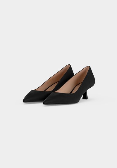 Paire de chaussures pour femmes noires à bout pointu et talon bas avec finition mate lisse sur fond neutre.