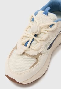 Lisse-sneakers med kremfarget mesh-overdel, beige semsket detaljer og en blå polstret krage. Inkluderer en snøring med justeringslås for enkel tilpasning.