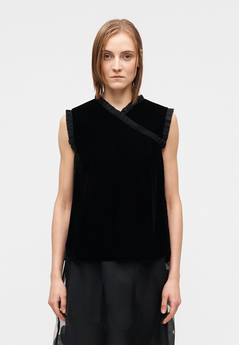 Svart sammetstopp utan ärmar med volangprydd halsringning och asymmetrisk design, med en mjuk textur och lös passform.