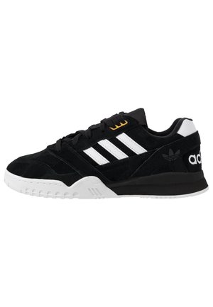 Baskets Adidas noires avec des bandes blanches, une semelle blanche et des lacets noirs, vues de profil côté droit.