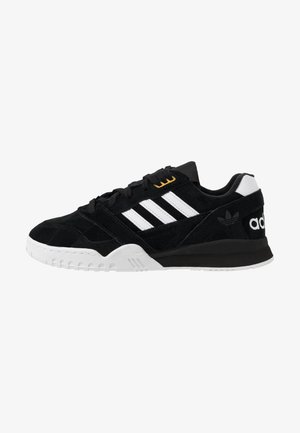 Zwarte Adidas-sneaker met witte strepen, witte zool en zwarte veters, gezien van opzij naar rechts.