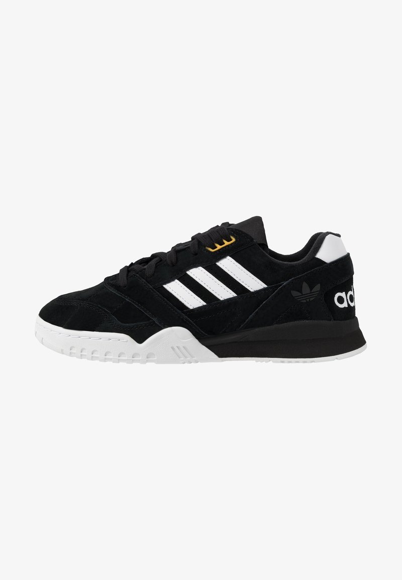 Baskets Adidas noires avec des bandes blanches, une semelle blanche et des lacets noirs, vues de profil côté droit.
