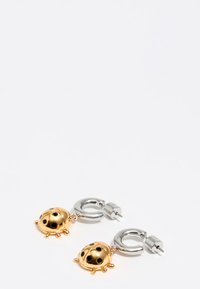 Pendientes de metal dorado y plateado en forma de mariquitas, con manchas negras y pequeñas patas, con un cierre de aro.