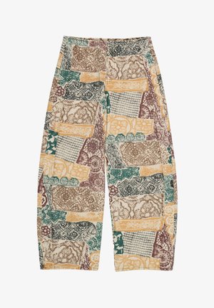 Pantalones holgados con un patrón de patchwork abstracto en beige, mostaza, verde, marrón y negro, con diseños variados de texturas y flores.