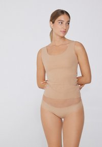 Beige bezešvý top s kulatým výstřihem a přiléhavým střihem, spárovaný s hladkými hipster kalhotkami ve stejném odstínu. Oba kusy mají jemnou texturu.