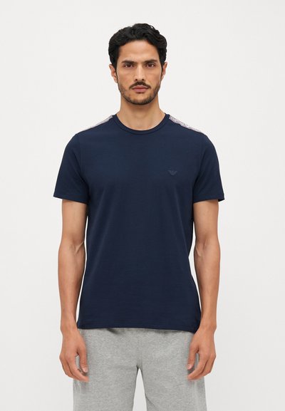 T-shirt en coton bleu marine à manches courtes, col rond et logo sur la poitrine. Présente des accents à motifs contrastants sur les épaules.