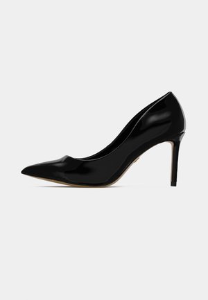 Décolleté in vernice nera con punta affusolata e tacco a stiletto sottile, visto di lato su uno sfondo semplice.