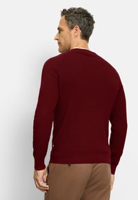 Burgundy knitted sweater with a textured pattern, ribbed cuffs, and hem. Simple design, no visible logos or embellishments.