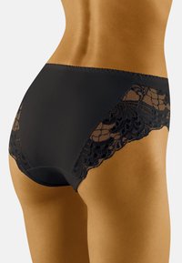 Culotte en dentelle noire avec un corps en tissu lisse, présentant des détails en dentelle intriqués sur les côtés. Conçue pour le confort et le style.