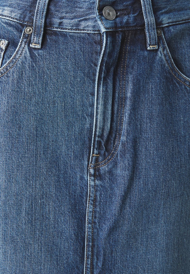 Jeans in denim con una finitura blu sbiadita. Presentano una chiusura con bottoni, passanti per cintura e tasche frontali. Tessuto liscio con dettagli di cucitura visibili.