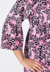 Rosa Kleid mit einem Leopardenmuster in Schwarz. Verfügt über Dreiviertelärmel und eine gefältelte Detail an der Taille. Weicher Stoff.