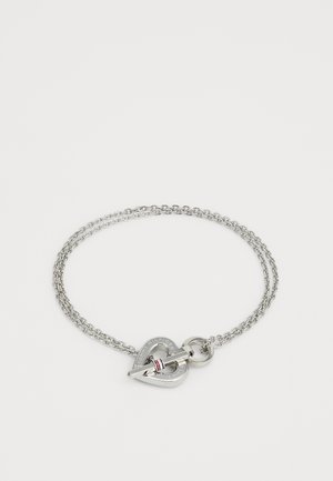 Pulsera de plata con un cierre en forma de corazón, que presenta un diseño de doble cadena, grabado del logotipo y un detalle de acento en rojo, blanco y azul.